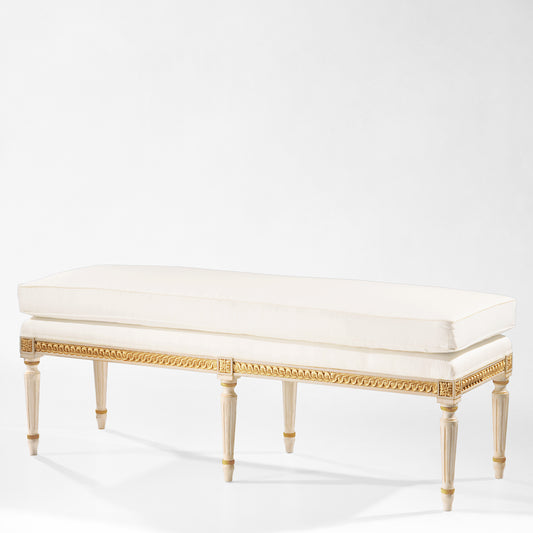 Antique white Italian bench with carved gold details and white fabric.