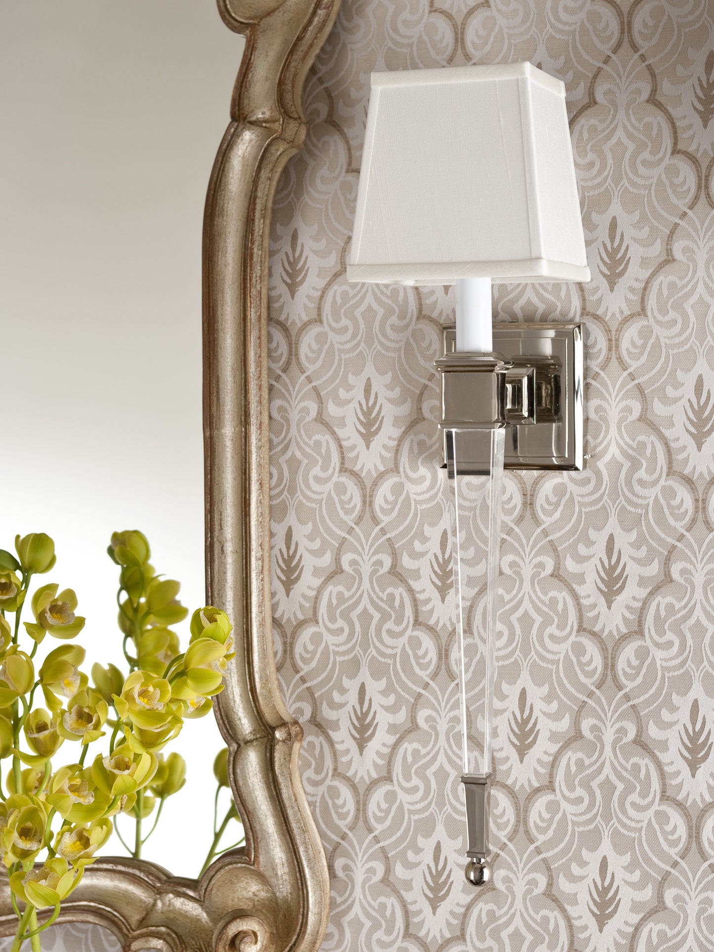 Crystal sconce on designer wallpaper next to mirror.