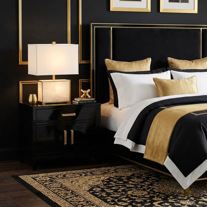 Luxurious bedroom with gold and black bedding, nightstand, and an alabaster lamp.