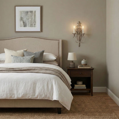 Neatly made bed with a silver sconce in a bedroom setting.