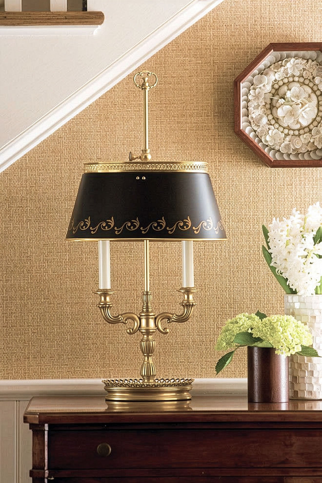 Antique brass bouillotte lamp with black shade in luxurious foyer.