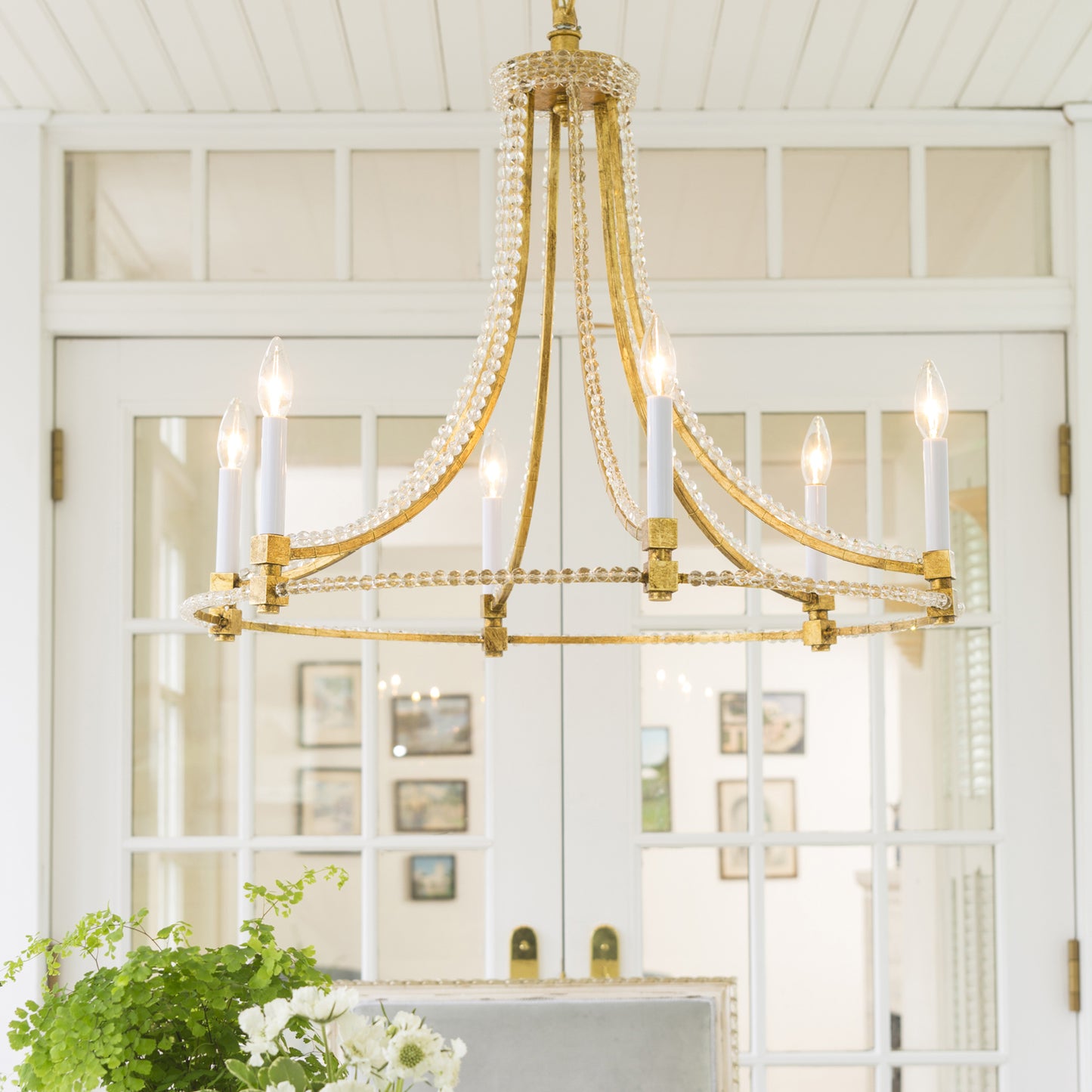 Gold Italian chandelier with crystals in white room.