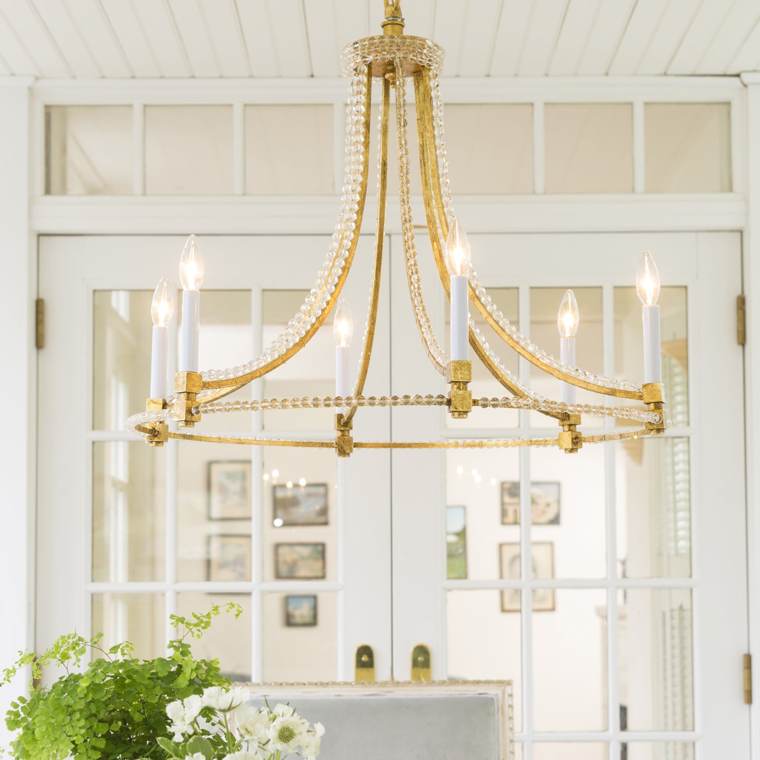Gold Italian chandelier with crystals in white room.