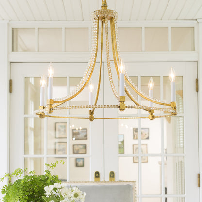 Gold Italian chandelier with crystals in white room.