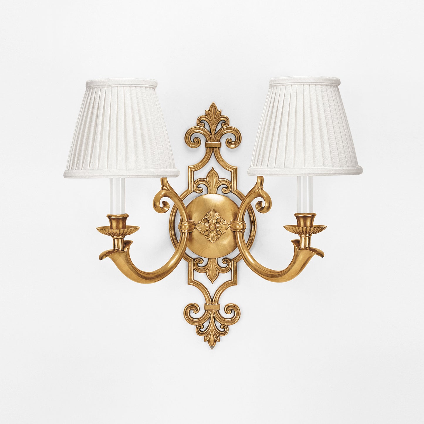 An antique brass sconce with pleated white shades.