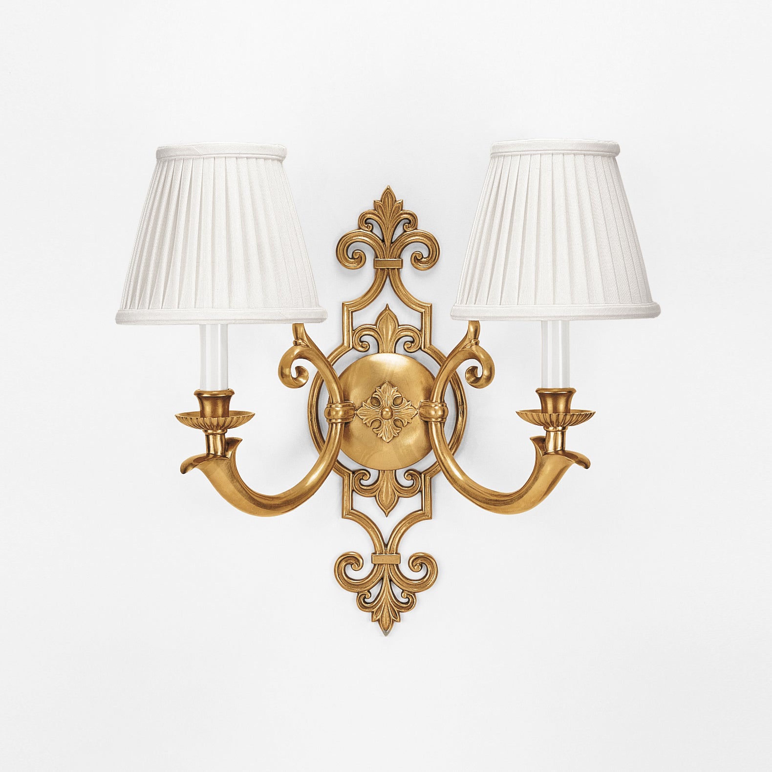 An antique brass sconce with pleated white shades.