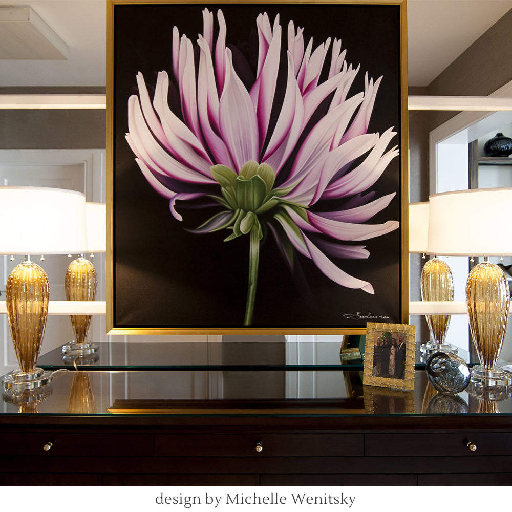 Framed pink flower artwork on a table with two amber Murano glass lamps and decor items.