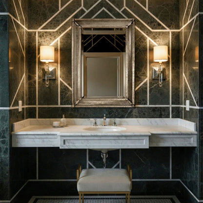 Antique Venetian glass mirror in a luxurious black marble bathroom with silver sconces.