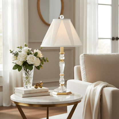 Decorative crystal and brass lamp on a marble table with flowers and books in a living room setting.