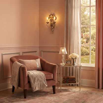 Cozy living room with a plush armchair, side table, and an antique silver-leaf sconce.