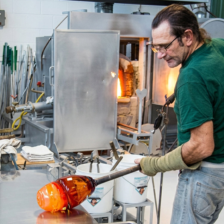 Glassblower making a Murano glass lamp in a Venetian glass workshop.