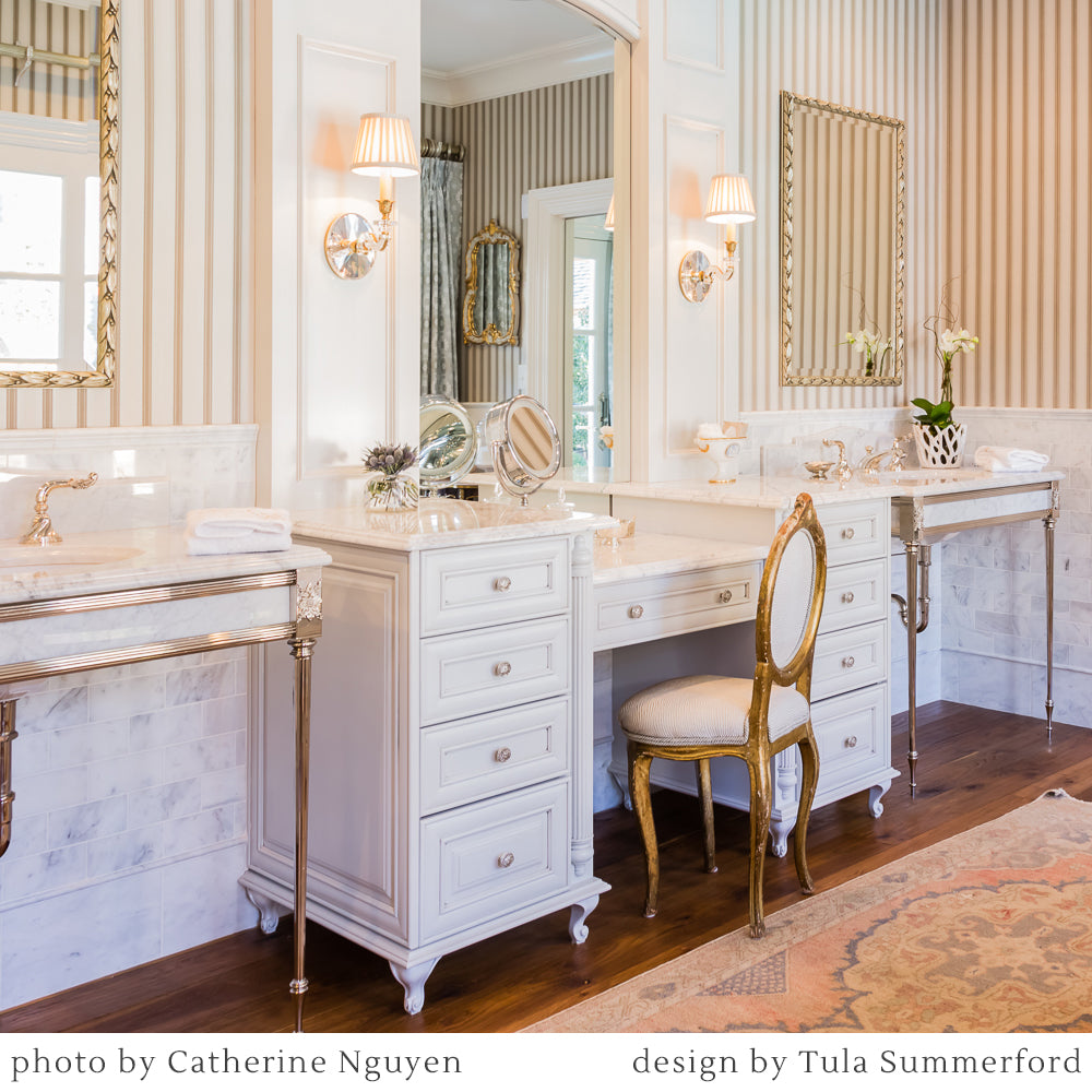 Antique Brass sconces in white bathroom with mirrors.