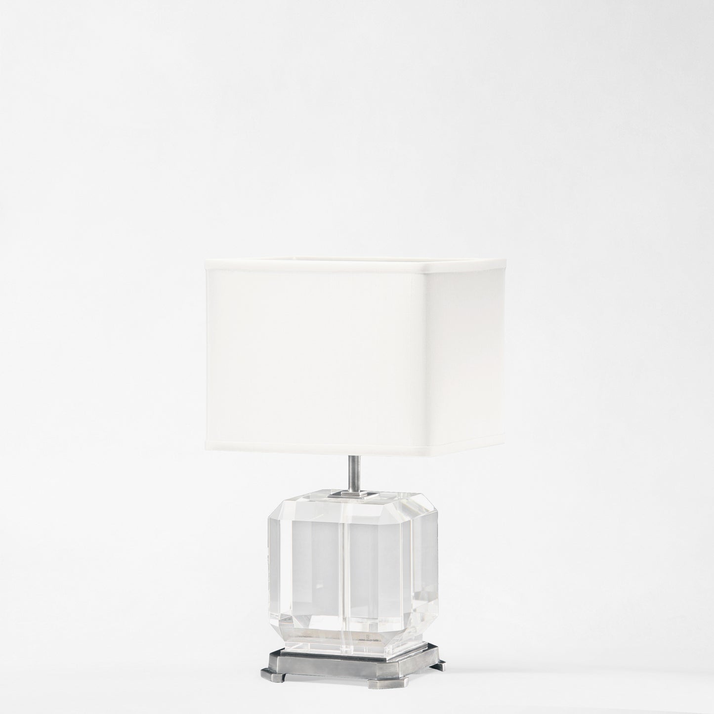 Crystal table lamp with polished nickel trim and white lamp shade.