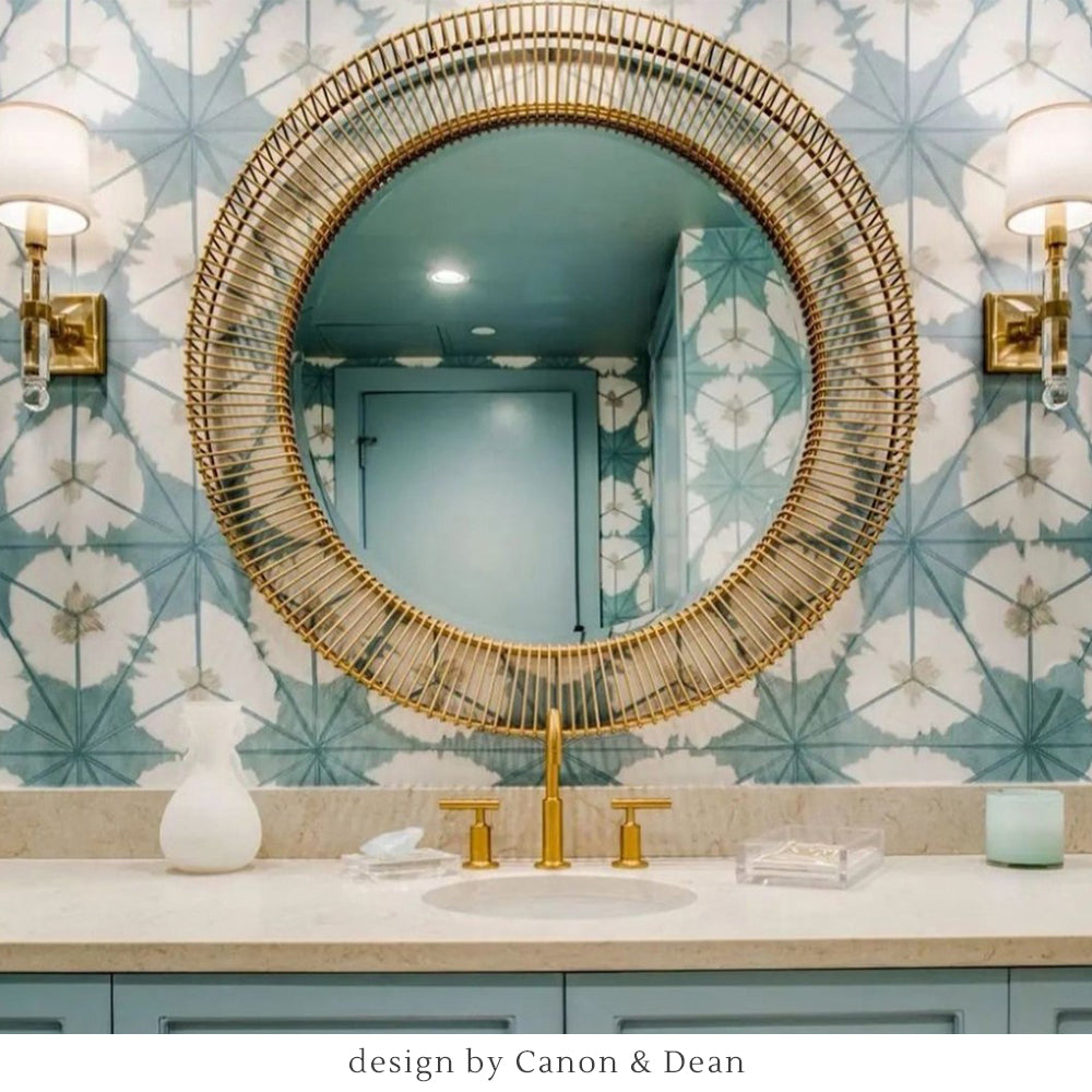 Crystal and antique brass sconces with gold mirror in a teal bathroom.