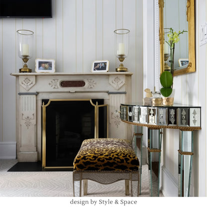 Brass fireplace screen in luxurious living room with gold mirror.