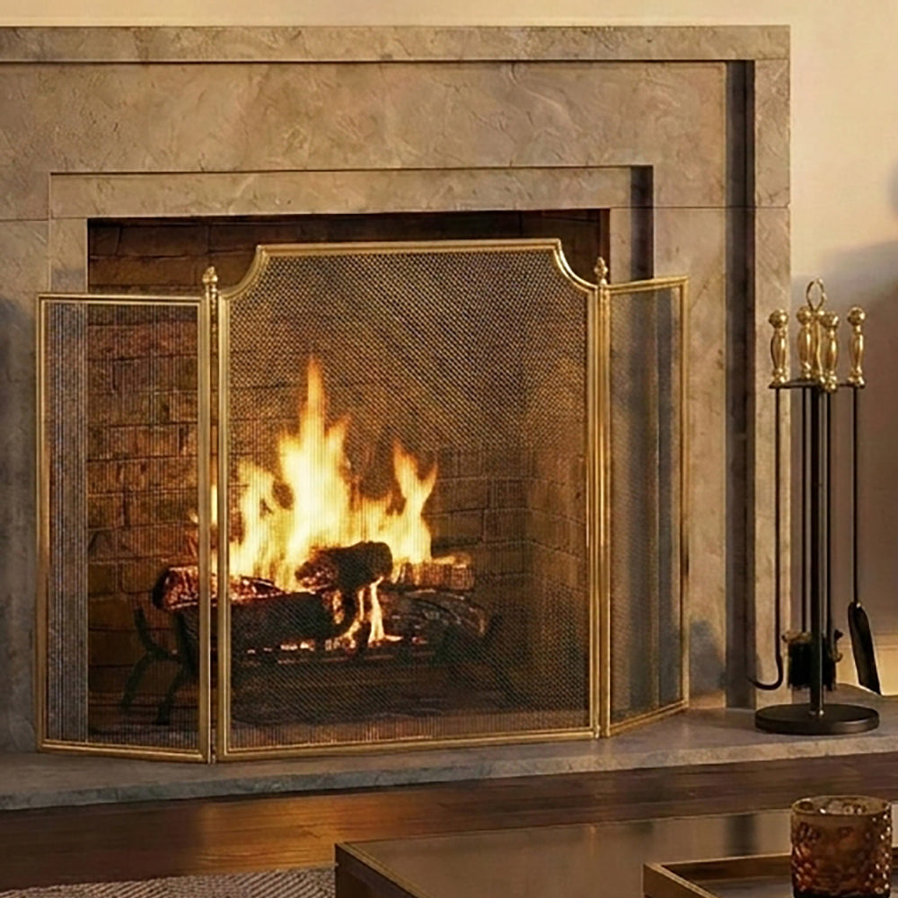 Brass fireplace screen next to brass fire tools in a luxurious living room.