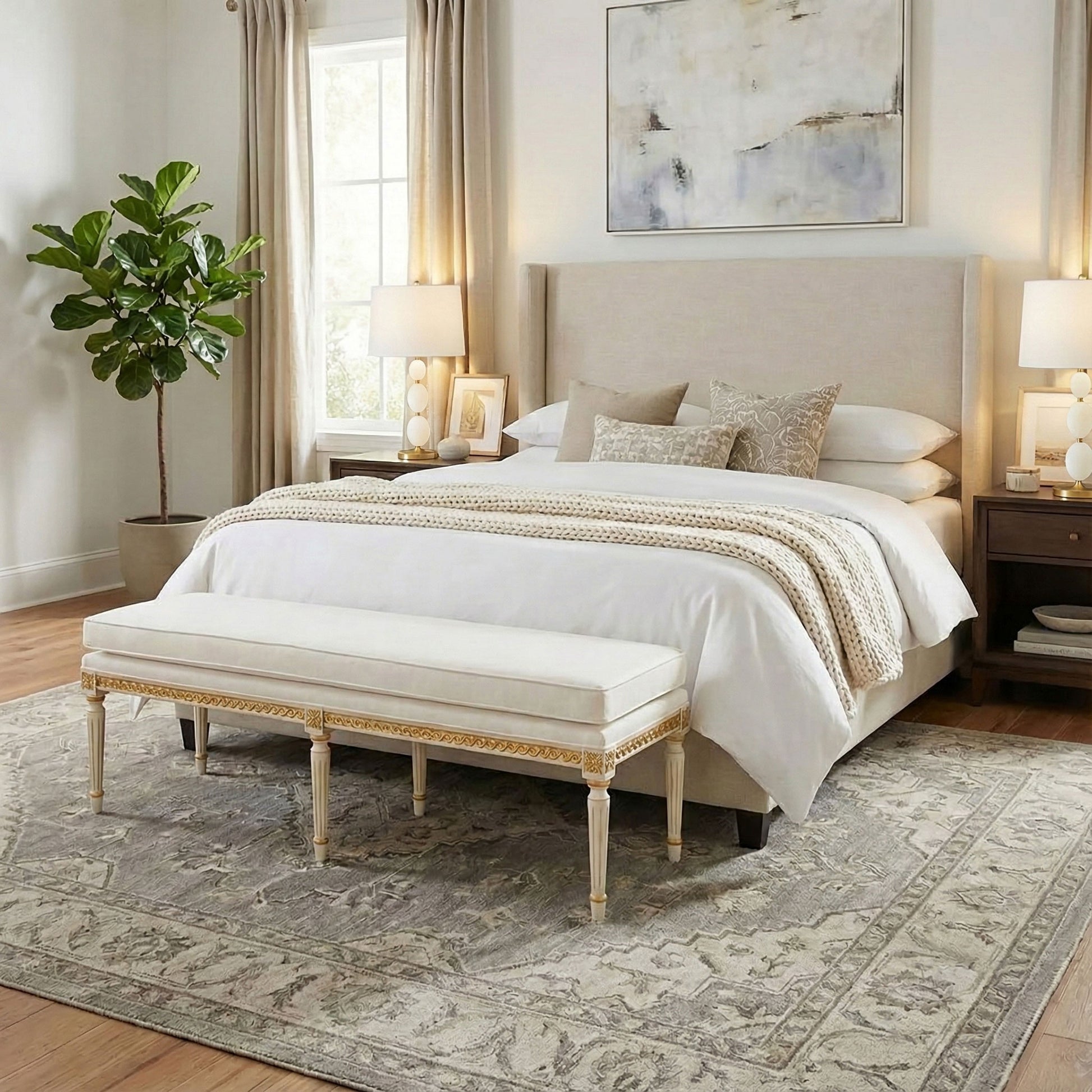 Neatly made bed with white bedding, alabaster lamps and a gold-leaf Italian bench in a bedroom setting.