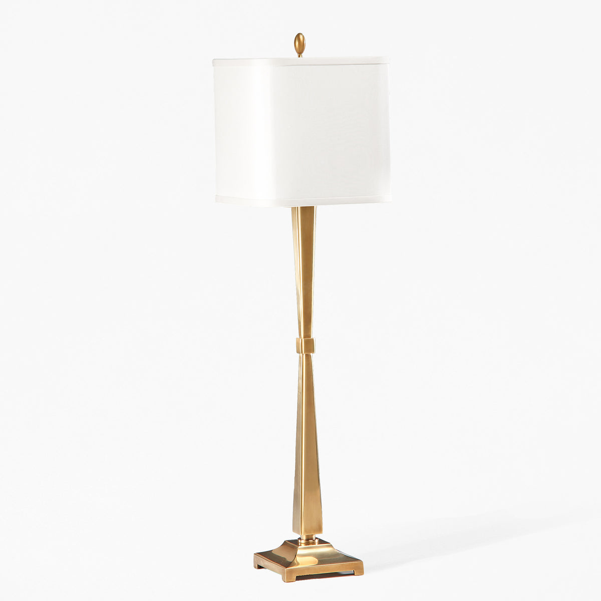 An antique brass table lamp with a square white shade against a grey background.