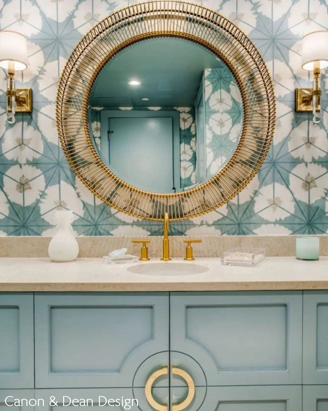 Crystal sconces with antique brass trim next to gold mirror in bathroom.