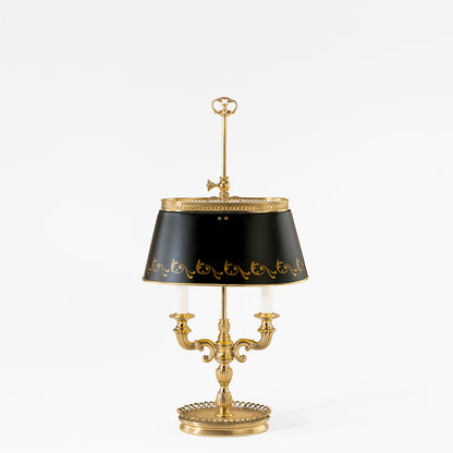 A traditional brass bouillotte table lamp featuring a black shade with ornate gold details.