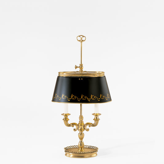 A traditional brass bouillotte table lamp featuring a black shade with ornate gold details.