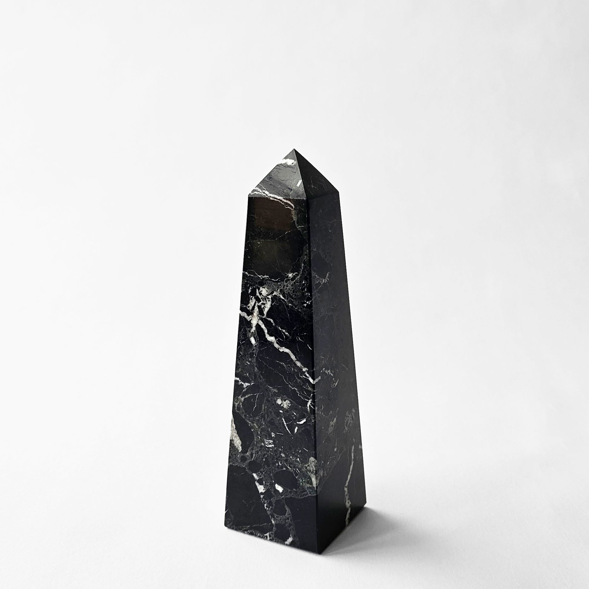 Black marble decorative obelisk with white veins.