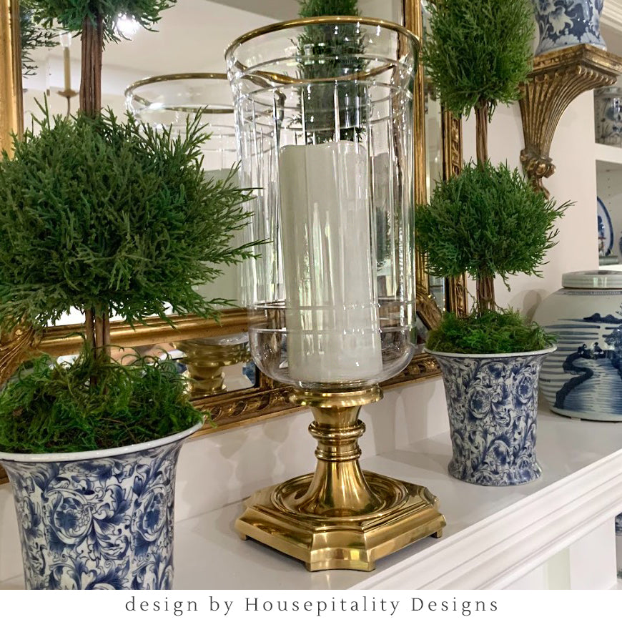 Brass hurricane on fireplace mantel with traditional decor.