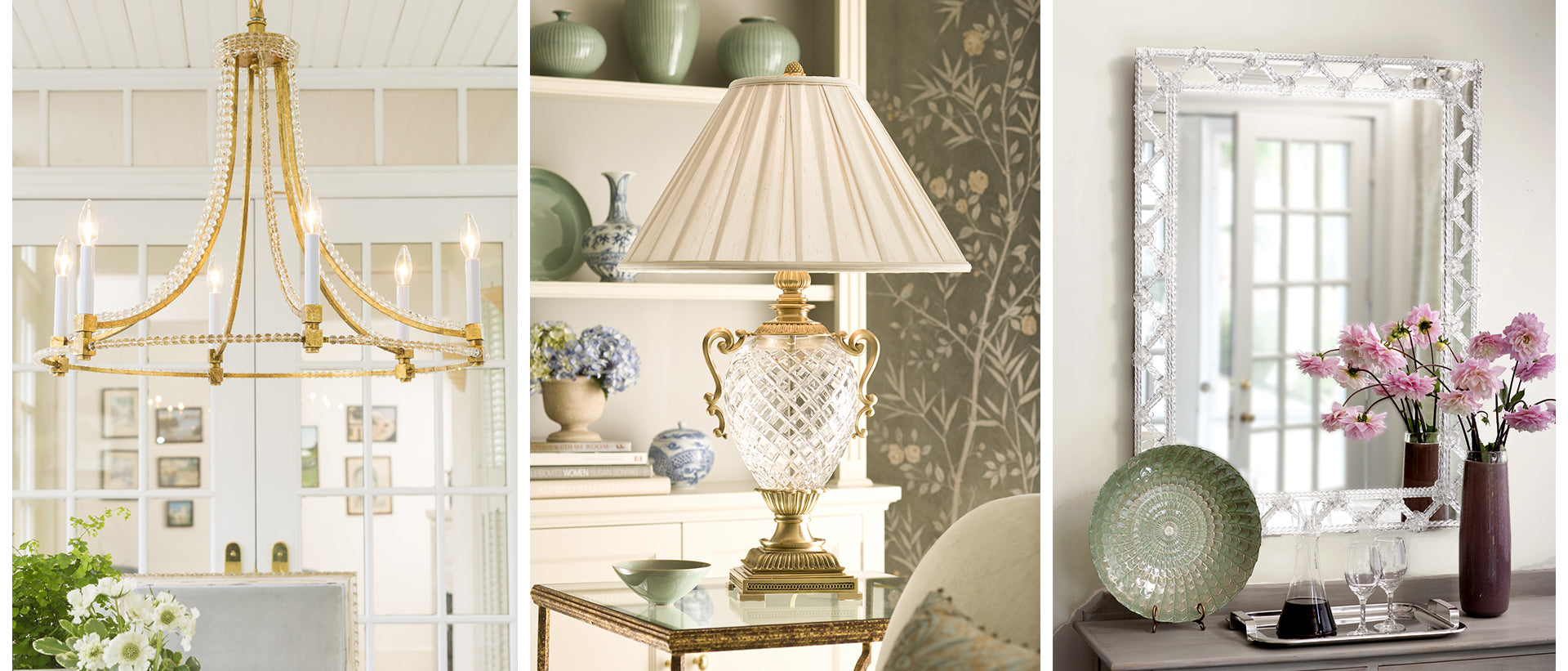 A gold chandelier in a bright room, a classic table lamp with a pleated white shade and ornate brass base, and a large Murano glass mirror above a console table with pink flowers.