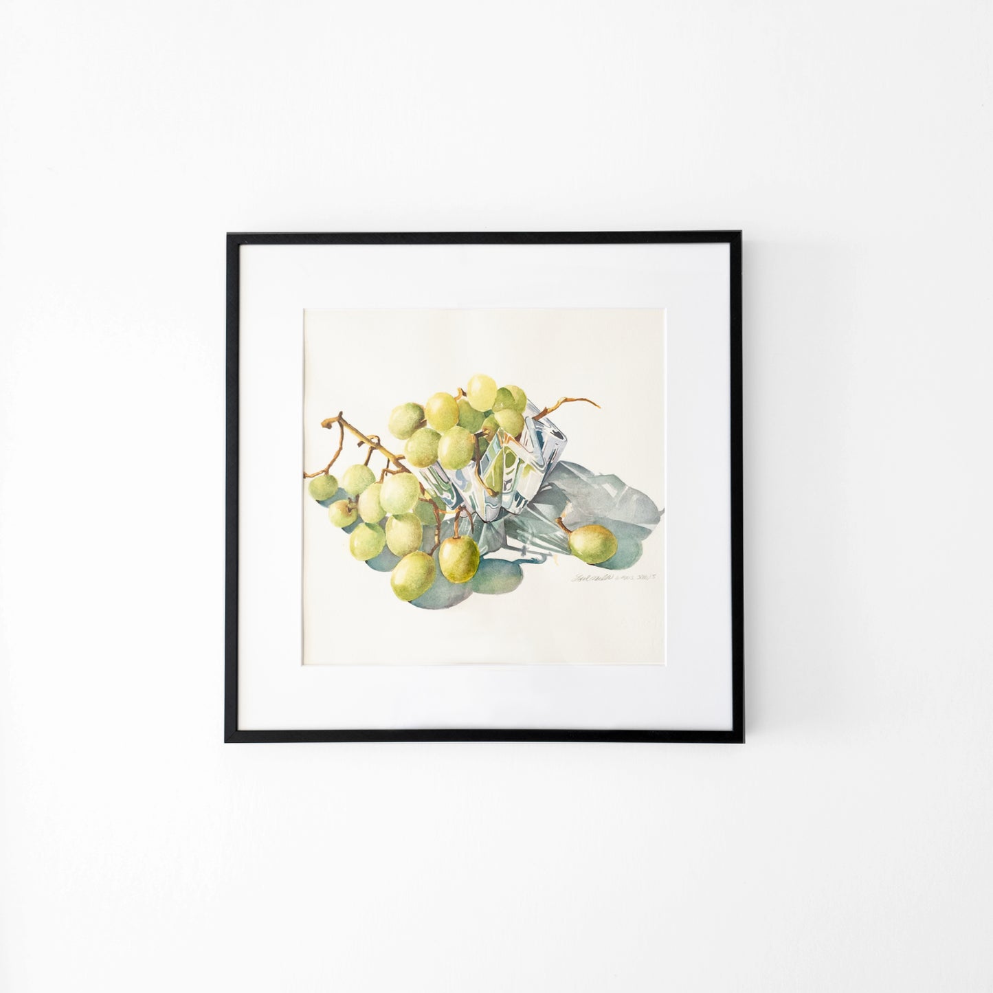 Watercolor painting of grapes in a crystal bowl in a back frame.
