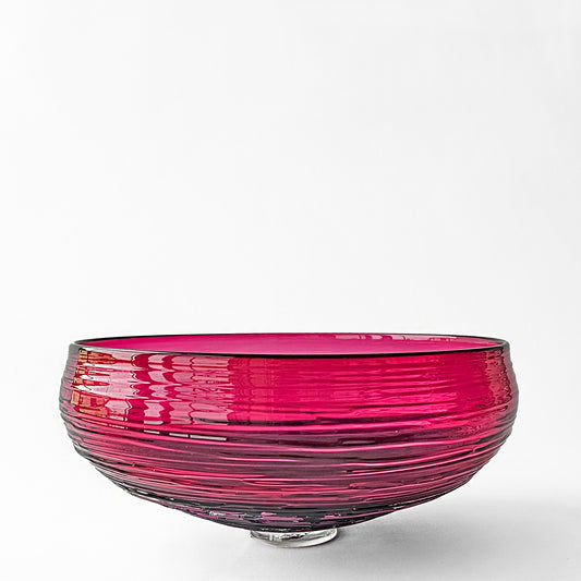 Magenta glass decorative bowl with ribbed design.