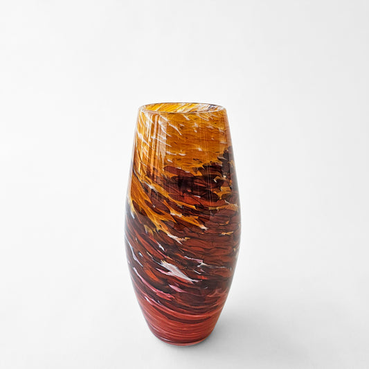 Orange red glass vase with swirl design.