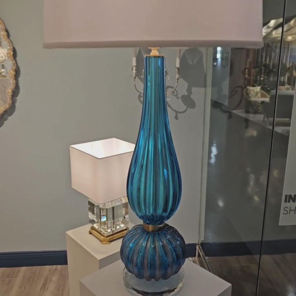 A blue Murano glass lamp with white lamp shade.