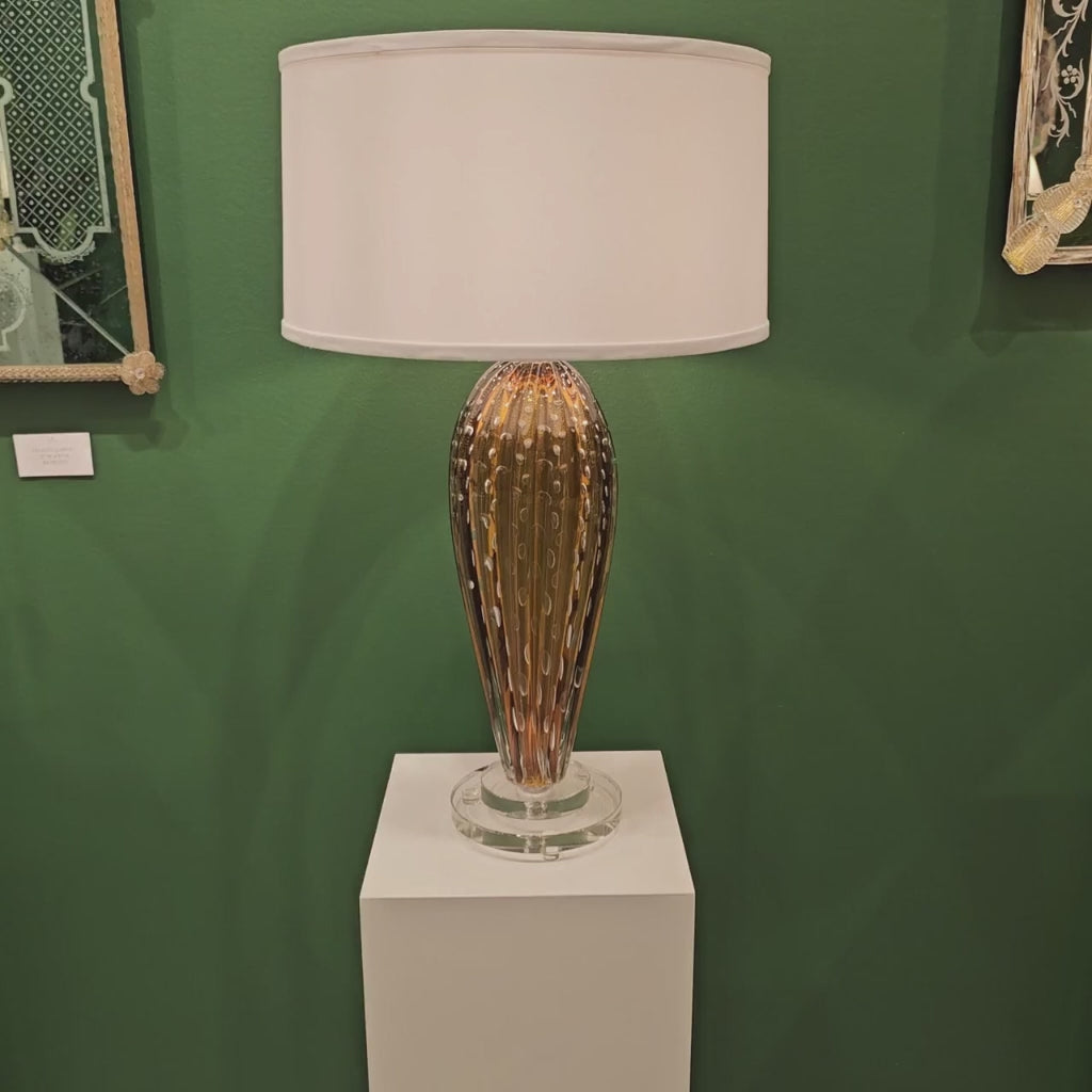 Amber Murano glass table lamp with white lamp shade.