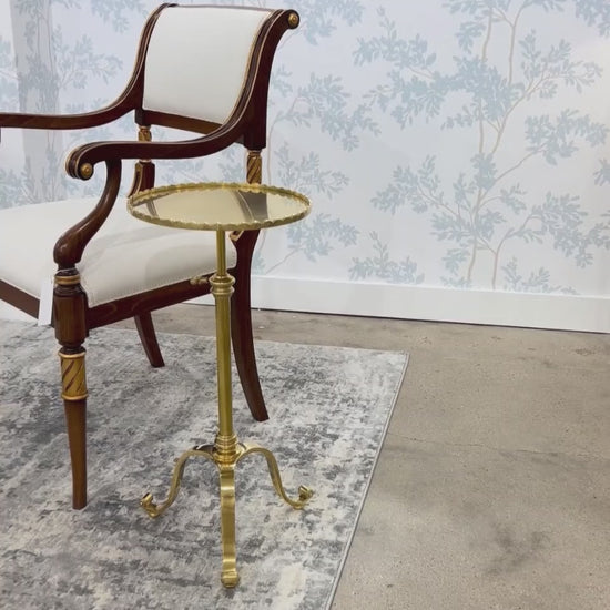 Brass accent table on rug next to Italian chair.