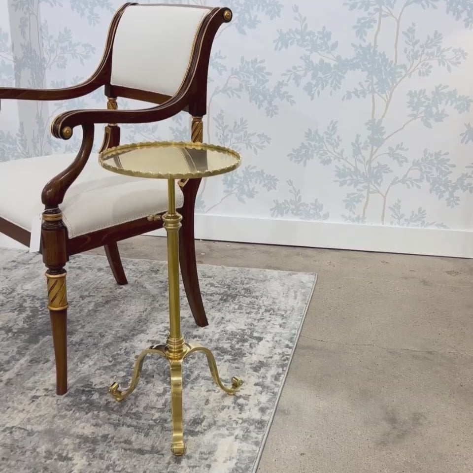 Brass accent table on rug next to Italian chair.
