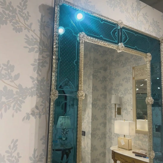 Antique blue Venetian glass mirror with luxurious wallpaper.