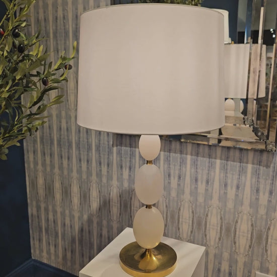 Brass and alabaster table lamp with white lamp shade.