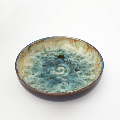 Dark blue ceramic decorative bowl with aqua crystalline glaze.