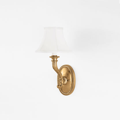 Traditional antique brass sconce with white shade.