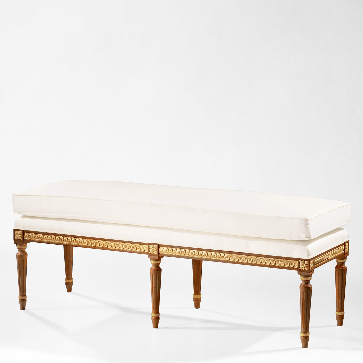 Traditional Italian wood bench with gold details and white cushion.