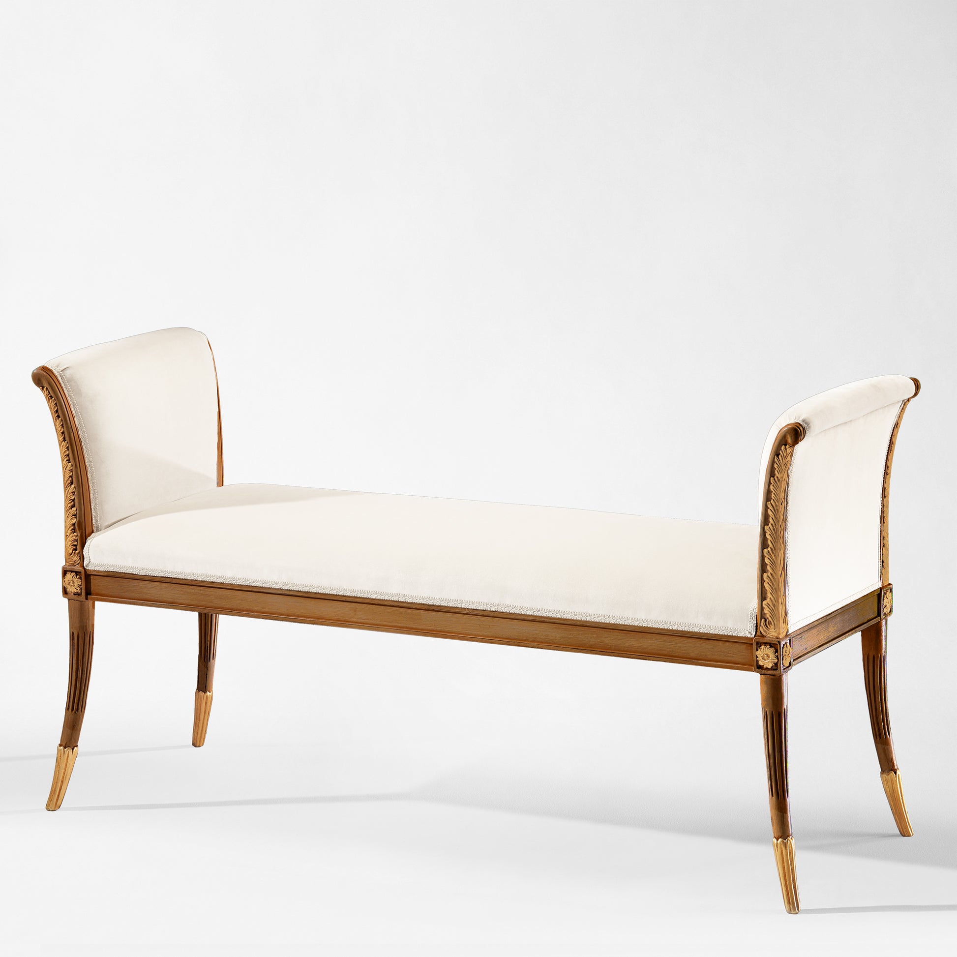 Italian carved wood bench with gold details and white fabric.